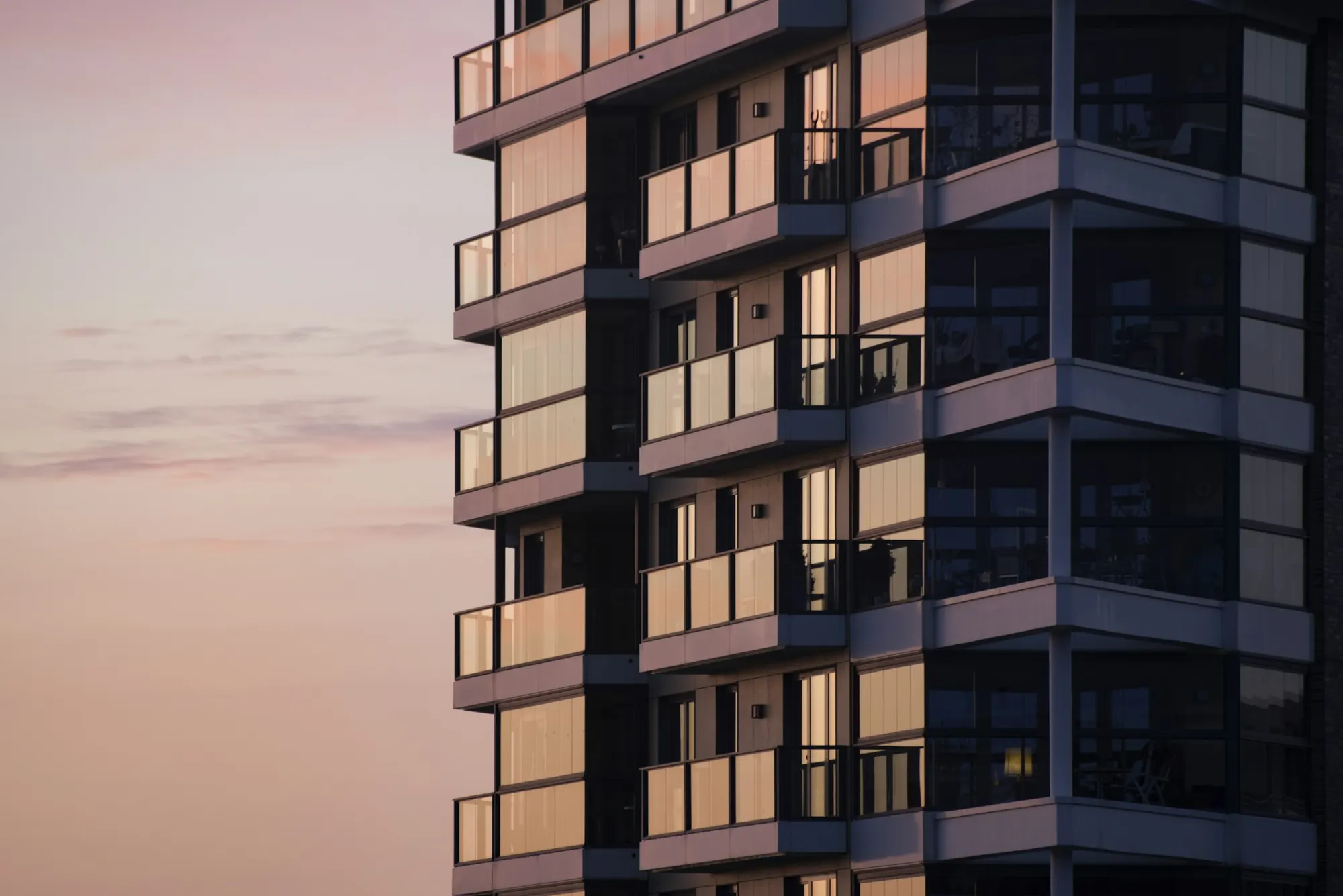 Un immeuble moderne aux balcons vitrés au crépuscule