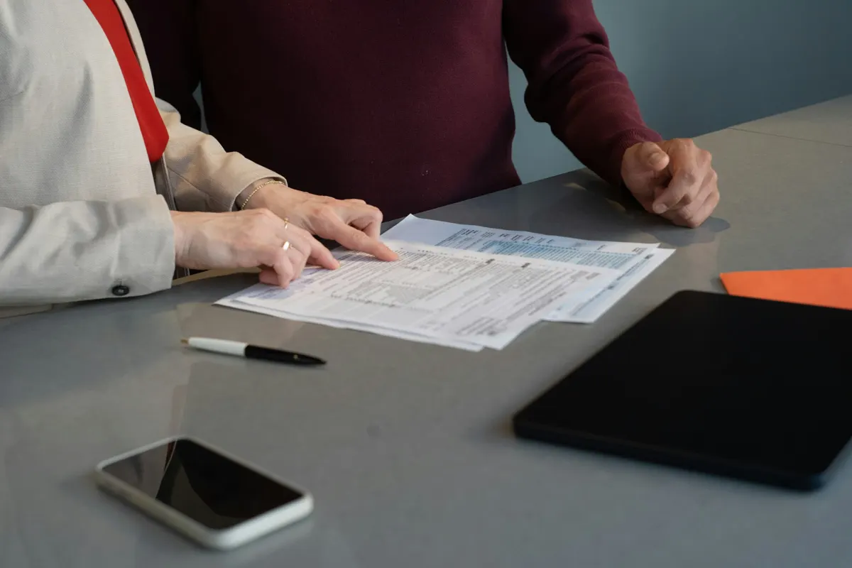 Deux personnes relisant des documents sur une table, mains et papiers